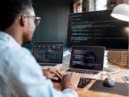 Man with two laptops and a screen with codes